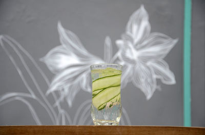 Vase on table against glass window with floral pattern