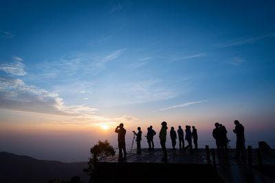 Silhouette people standing against sky during sunset