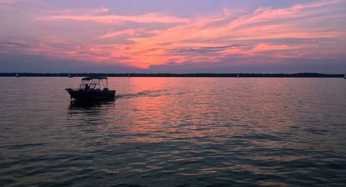 Boat sailing on sea against sky during sunset