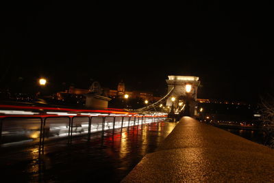 Illuminated bridge over river against sky at night