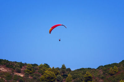 Low angle view of paragliding against clear blue sky