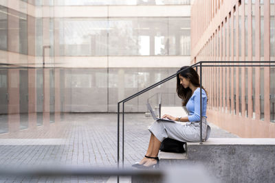 Young woman using mobile phone while sitting in office