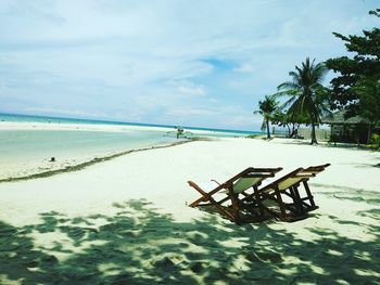 Deck chairs on beach against sky