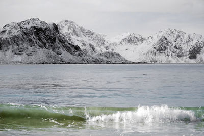 Scenic view of sea and snowcapped mountains against sky