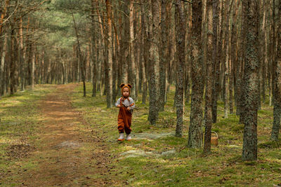 Toddler baby boy in bear bonnet sitting in the woods