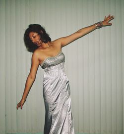 Portrait of smiling young woman standing against wall