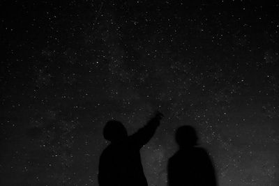 Silhouette people standing against star field at night
