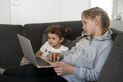 Sisters on sofa using laptop