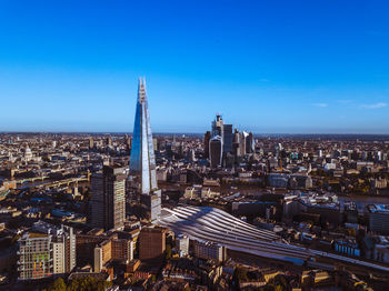 High angle view of city buildings against blue sky