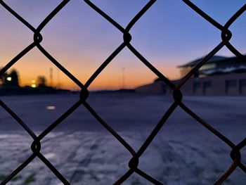 Full frame shot of chainlink fence against sky during sunset