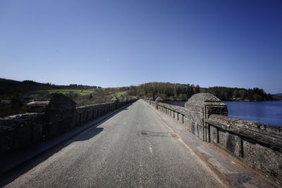 Empty road against clear blue sky