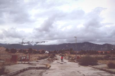 Man standing on street in city against sky