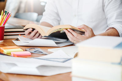 Midsection of man reading book on table