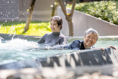 Rear view of people enjoying in water