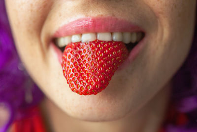 Close-up of woman face holding strawberry outdoors