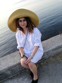 Portrait of smiling young woman sitting against sea