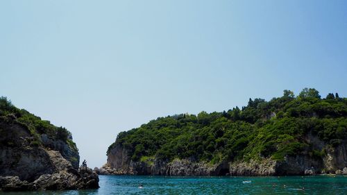 Rocky cliff with sea against clear sky