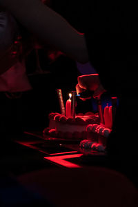 Cropped hand of person holding illuminated candles on table