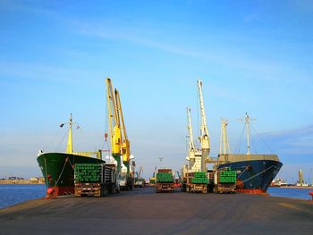 Cranes at harbor against clear blue sky