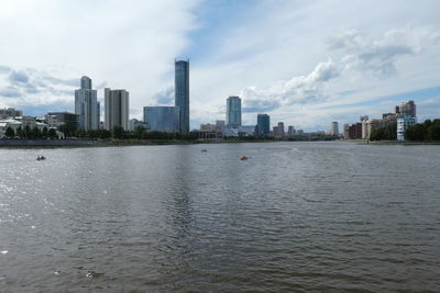 Sea and buildings in city against sky