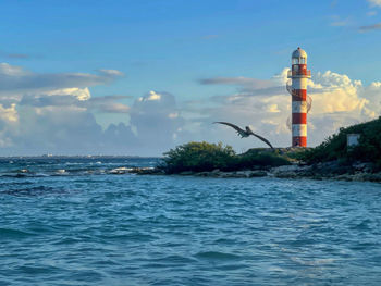 Lighthouse by sea against sky