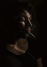 Close-up of mid adult man smoking cigarette against black background