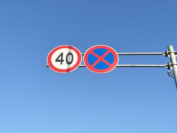 Low angle view of road sign against clear blue sky