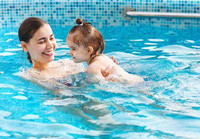 High angle view of mother and daughter swimming in pool