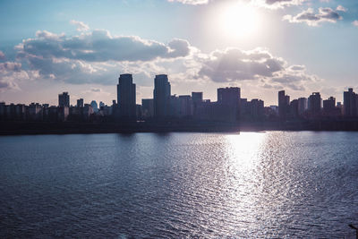 Sea by buildings against sky in city