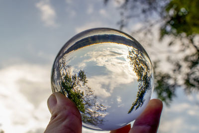 Midsection of person holding glass against sky