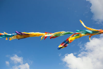 Low angle view of colorful flying against blue sky