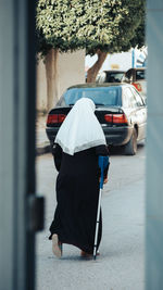 Rear view of woman with umbrella walking on street