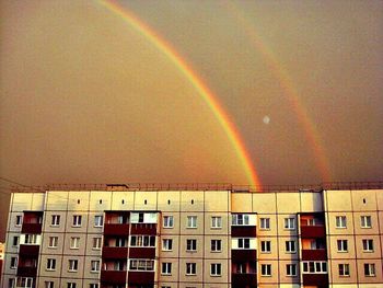 Low angle view of rainbow over building against sky