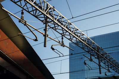 Low angle view of crane by building against clear sky