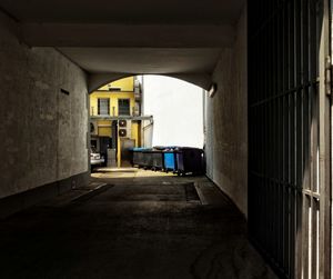 Wheeled garbage can by building seen through tunnel