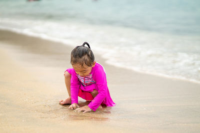 Girl playing with sand at beach