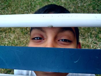 Portrait of boy by fence on field