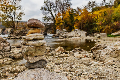 Stone stack on rock by river against sky