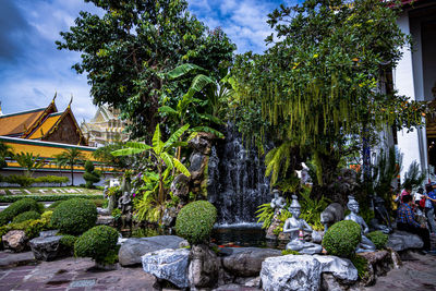 Statue in garden by building against sky