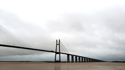 View of suspension bridge against cloudy sky