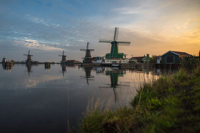 Lake against traditional windmills in town during sunset