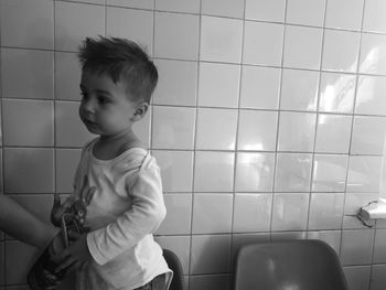 Side view of boy standing by tiled wall