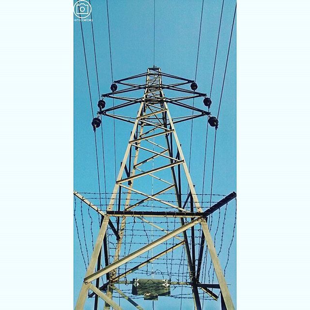 low angle view, clear sky, blue, built structure, metal, copy space, connection, day, transportation, part of, no people, architecture, outdoors, sky, engineering, metallic, cropped, railing, sunlight, directly below