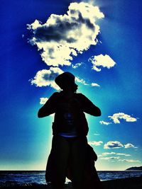Low angle view of man standing against blue sky
