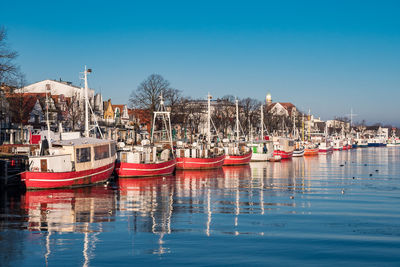 Boats moored at harbor against clear blue sky