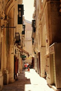 Man walking in alley amidst buildings