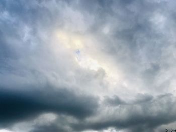 Low angle view of sunlight streaming through clouds