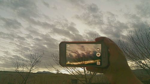 Close-up of smart phone against sky