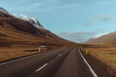 Road leading towards mountains against sky