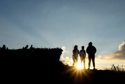 Silhouette people standing against sky during sunset